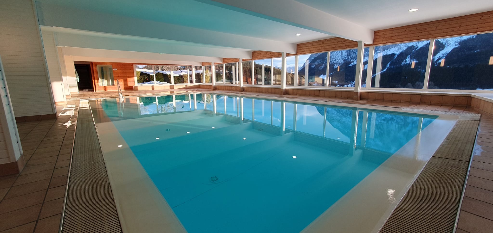 Vnitřní bazén s prosklenou stěnou a výhledem na hory